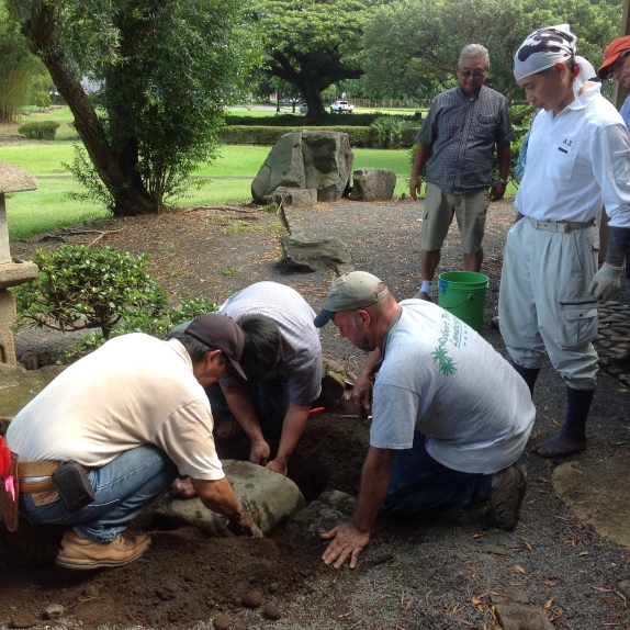 David Tamura and his son Troy and Robert Frost re-set a stone at Takuhiro Yamada's direction